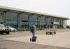Letiště Darwin (DRW): doprava, aerolinky a tipy Terminální budova letišti Darwin s cestujícím nesoucím kufr a batoh přicházejícím k vchodu